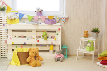 kids playroom with teddy bear, toys carpet, book and white furniture closeup photo