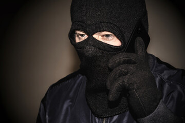 An extortionist in black clothes with a balaclava covering his face. A cruel fraudster uses a...