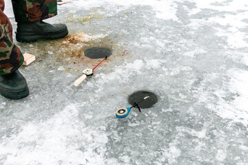 Naklejka premium Winter fishing rods lie on holes drilled in the ice. Winter fishing on the pond.