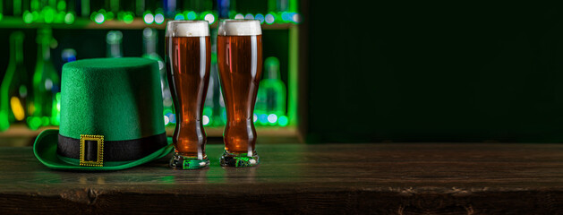 Tall glasses of cold beer, ale on the bar counter. Holiday of Ireland on St. Patrick's Day in irish pub, bar. Festive Leprikon's green hat. National tradition of carnival celebrating March 17