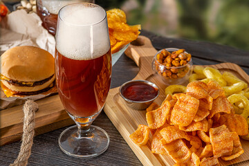 Glass of beer on bar counter. Jugs, mugs, pints of brew beverage, ale, cider on wooden table in...