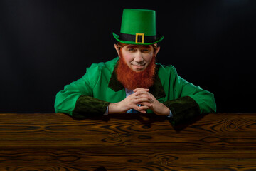 Leprechaun elf on St. Patrick's Day. Cheerful character Irish leprechaun for advertising with a red...