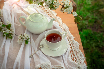 Obraz na płótnie Canvas Tea set, cherry blossom branches, wooden table. Outdoor breakfast, picnic, brunch, spring mood. Soft focus