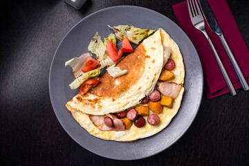 Fried eggs with sausages in olive oil. Hearty breakfast