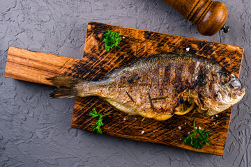 grilled dorado is served on a wooden board with vegetables