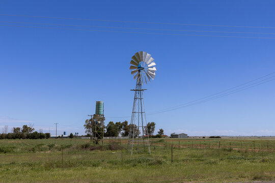 Wind pump also known as a wind mill in a rural area, being it is a green plastic storage tank to contain the water that is extracted from the earth 