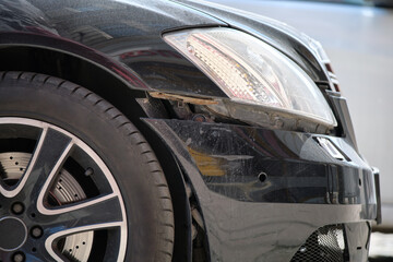 Dented car with damaged fender parked on city street side. Road safety and vehicle insurance concept