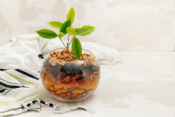 Round glass vase with a mix of nuts and dried fruits, green sprout, tallit, symbolizing the Jewish...