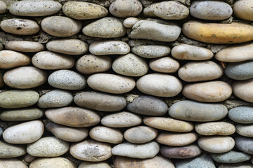 Full frame image of fence made of gray sea pebbles. Close-up front view. Natural wallpaper, background or texture