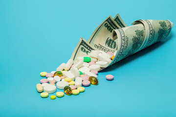 Money and pills of different colors on a blue background. The rise in the cost of medical care. The concept of insurance medicine, insurance, high cost, high cost of drugs.