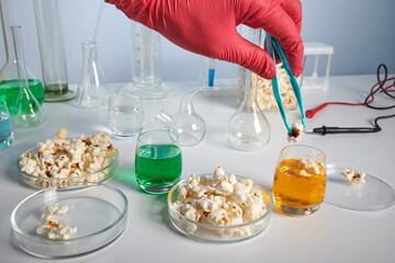 Hand takes pop corn from petri dish for test in a lab. Pop corn under investigation on test lab...