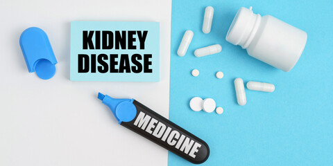 On the white and blue surface are pills, a marker and paper with the inscription - KIDNEY DISEASE