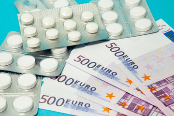 Money pills. Medicine pills on euro bills on a blue background. Covid-19 coronavirus pills are in euro money. The concept of insurance medicine, insurance, high cost, high cost of drugs.