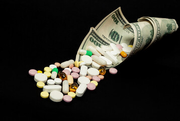 Money and pills of different colors on a black background. The rise in the cost of medical care. The concept of insurance medicine, insurance, high cost, high cost of drugs.