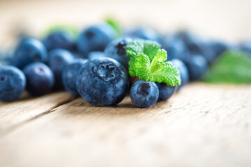 Close-up of fresh blueberries with mint leaves on wooden background. Superfood concept