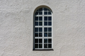 Fototapeta na wymiar Large vaulted window on a sunny white wall