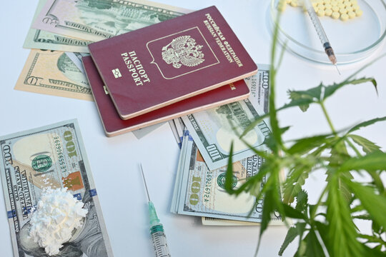 Russian passport with dollars and illegal drugs. Criminal photo is made with cocaine flour and cannabis plant leaves. Cocaine dust on 100 dollar banknotes. Elements of criminal trip. Business on