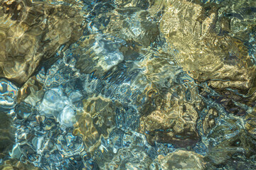 Beautiful blue and yellow texture of color smooth stones with water is in the lake