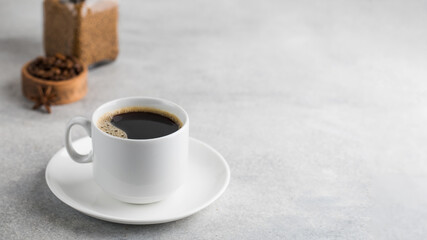  Black instant coffee in a white mug on a gray background. Copy space.