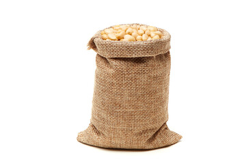 Siberian, Peeled pine nuts in burlap bag isolated on white background. Healthy nuts snacks. Clipping path, full depth of field. Closeup view.