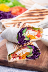 Grilled chicken wraps with red cabbage, avocado, tomato, lettuce, cheddar cheese, closeup