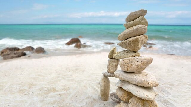 Zen stones stack balanced on beach with sea and clear blue sky in background. Summer day on one of the Kassandra peninsula beaches in Halkidiki, Greece.