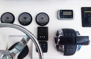 Luxury yacht control panel with steering wheel, gear levers, navigation devices and control buttons.