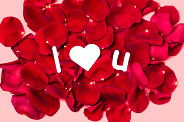 Paper message on red rose petals reads "I heart you" valentine simple design