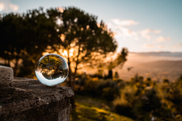 Bola de cristal aislada en un extremo y arboles reflejados en un atardecer que nos deja ver la sombra de estos