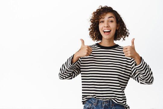 Beautiful cheerful girl showing thumbs up in approval, like gesture, agree, recommending great store, praising and complimenting, white background
