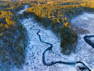 aerial view of winding river in forest after snow under sunlight