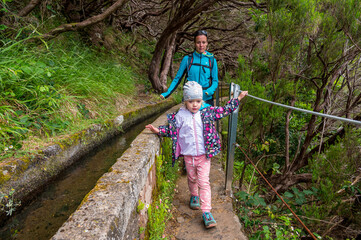Mother and daughter walking along forest path with safety rail.