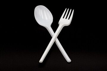 White plastic spoon and fork isolated on black