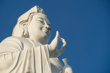 Detail of Lady Buddha statue in a Buddhist temple and blue sky background in Danang, Vietnam.