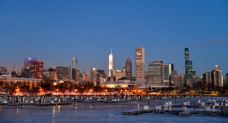 Obraz premium Sunrise reflections on the big city skyline along the frozen waterfront in winter