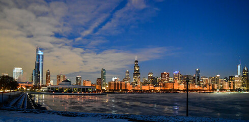 Fototapeta na wymiar Sunrise reflections on the big city skyline along the frozen waterfront in winter