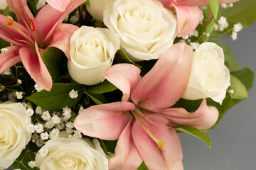 A beautiful bouquet of pink lilies and white roses on background is a blank for congratulations or invitations.