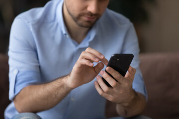 Cropped close up man using smartphone, typing on screen, focus on modern phone in male hands, chatting with friends in social network, browsing mobile device apps, playing game, shopping online