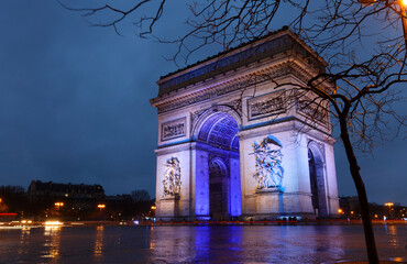 Fototapeta na wymiar The Triumphal Arch illuminated in the colors of the European Union flag to mark the start of France presidency of the EU at rainy night, Paris.