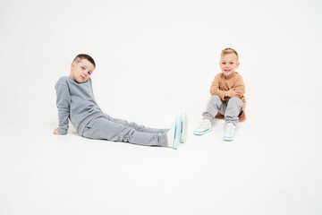 The boys sit on a monochromatic background. Children in sportswear. Children rest after an active workout.
