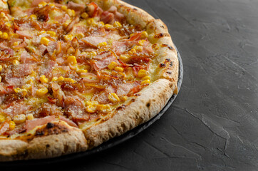 Ham and corn pizza prepared in a wood-fired oven.