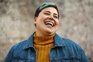 A young woman of non-binary sexuality smiles showing her teeth