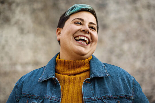 A young woman of non-binary sexuality smiles showing her teeth