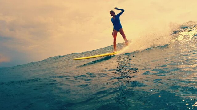 Woman surfs the wave in the ocean on the longboard. Sultans surf spot in Maldives