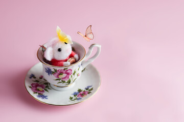 Topolino di lana nella tazza gioca con la farfalla
