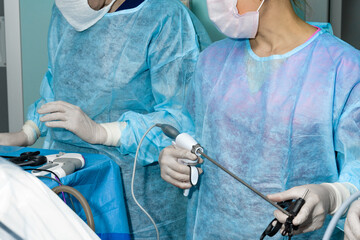 The surgeon holds a surgical laparoscopic manipulator in his hands. Selective focus. Minimally invasive laparoscopic proctological surgery. A doctor in uniform and gloves uses a surgical instrument.