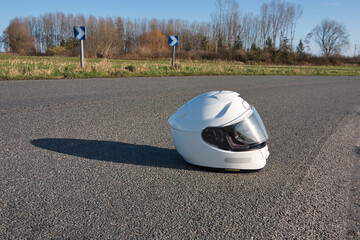 casque moto blanc  poser au sol sur route départemental - obrazy, fototapety, plakaty