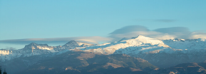 Spectacular lenticular clouds over the peaks of Sierra Nevada (Spain) at sunset in winter