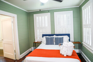 A green bedroom bedroom with a king sized bed and a fan at a short term rental small cottage style house
