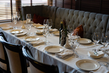 tableware Glasses, flower fork, knife served for dinner in restaurant with cozy interior.